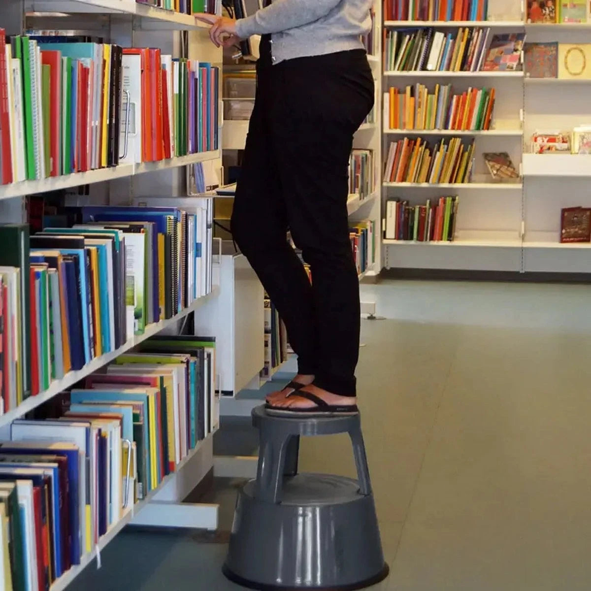 Elefantfod mørk grå skammel bruges i et bibliotek, set nedefra.