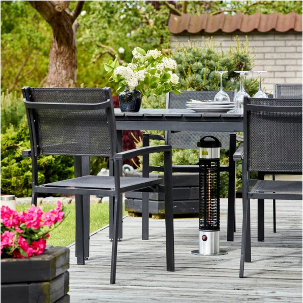 Terrassevarmer 1200W under bord på træterrasse med grå møbler og grønne planter